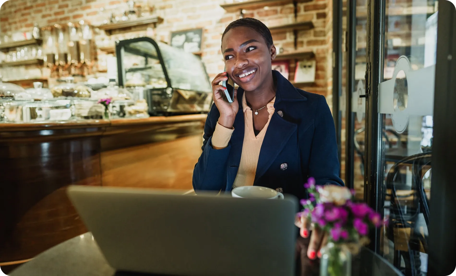 Smiling café owner taking a call at her counter